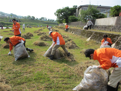 写真: 住民の方と一緒に河川敷の草を刈り集め、搬出。