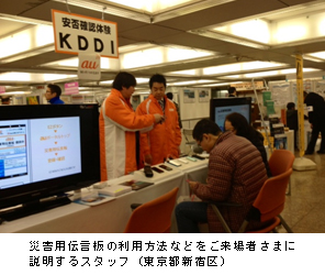 写真: 災害用伝言板の利用方法などをご来場者さまに説明するスタッフ (東京都新宿区)