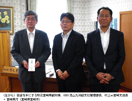 写真: (左から) 目録を手にする牧元宮崎県副知事、KDDI児山九州総支社管理部長、村上au宮崎支店長 = 宮崎県庁 (宮崎県宮崎市)