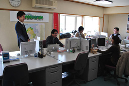 写真: 東松島みらいとし機構の事務所で挨拶をする復興支援室福嶋正義課長補佐 (左) ＝ 東松島市役所 (宮城県東松島市)