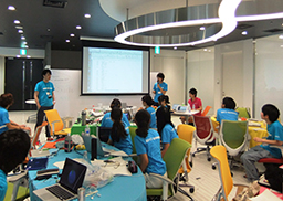 写真: KDDI社員のアドバイスを受けながら、アイデアを練る中高生の皆さん