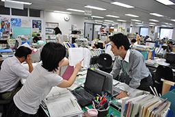 写真: 配属先で業務を行う復興支援室 加藤英夫課長補佐 (右)